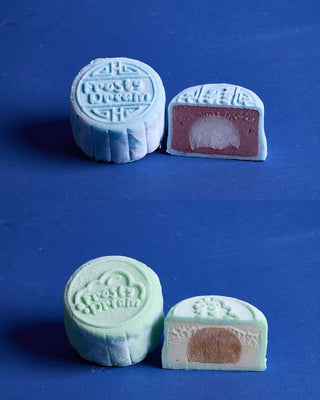 Cross-section of two snowskin gelato mooncakes side by side. Left: pale blue Berry Lemon shell with mixed berries sorbetto and lemon filling. Right: pale green Mango Tango shell with mango yogurt gelato and passionfruit filling.